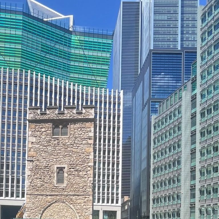 Medieval stone church tower in front of tall modern office buildings
